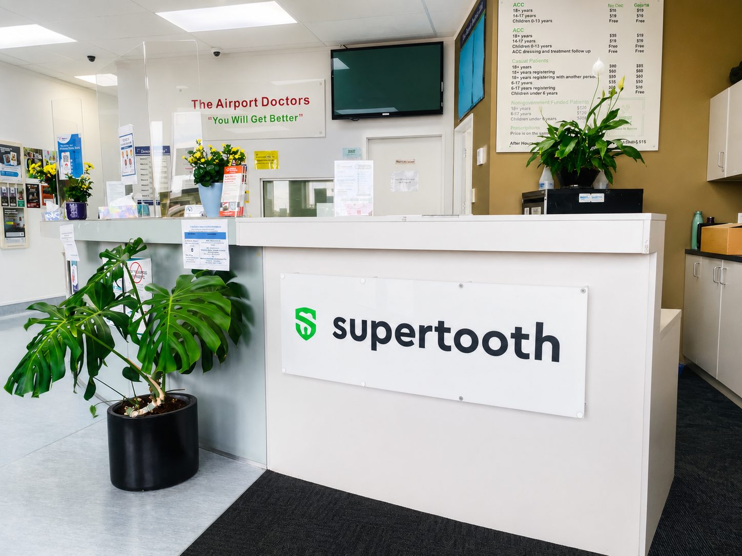 Reception desk at Supertooth Dental with branded signage and plants