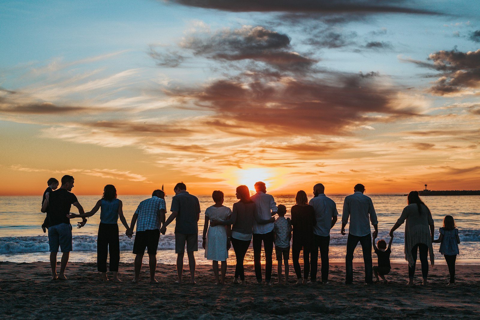 A whānau together on the beach at sunset