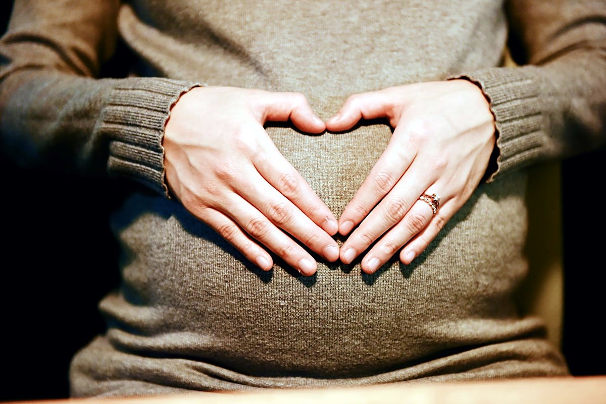 An expectant mother resting her hands on her bump